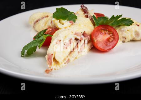 Omelette con Prosone e formaggio su fondo di legno nero Foto Stock