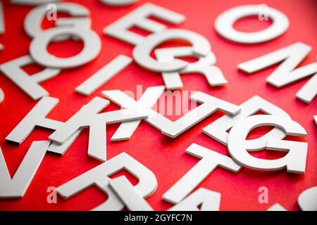 Le lettere piene miste impilano la foto in primo piano. Concetto di istruzione su sfondo rosso. Foto Stock