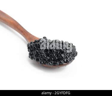 caviale fresco di pesce paddlefish nero granato in cucchiaio di legno marrone su sfondo bianco, primo piano Foto Stock