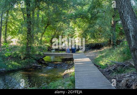 Fiume Gevora, la Codosera, Badajoz, Estremadura, Spagna. Coppia anziana seduta su ponte di legno Foto Stock