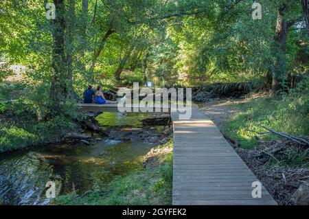 Fiume Gevora, la Codosera, Badajoz, Estremadura, Spagna. Coppia matura seduta su ponte di legno Foto Stock