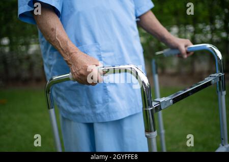 Donna anziana o anziana anziana asiatica usano il walker con la salute forte mentre cammina al parco in una felice vacanza fresca. Foto Stock