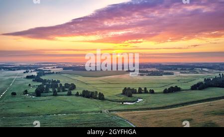 Spettacolare alba estiva. Panorama nebbiosa paesaggio. Mattina nebbia sulla vista aerea del fiume. Campi verdi e prati. Drone foto per concetto ecologico. B Foto Stock