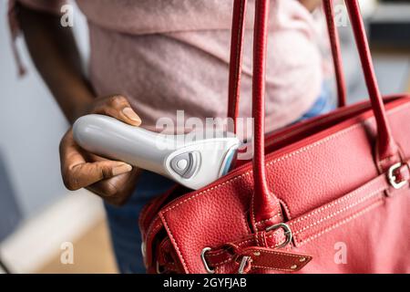 Donna che ruba il richiamo dei piedi elettrici nel negozio al dettaglio. Furto di taccheggio crimine Foto Stock