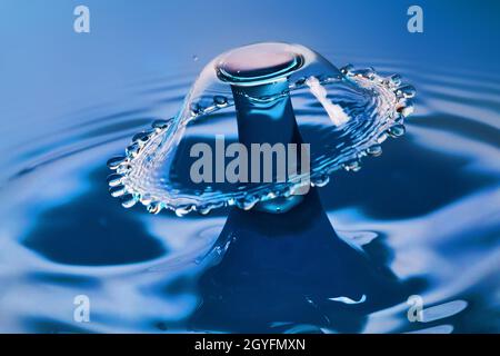 Bellissimo ombrello di acqua da collisione acqua su acqua blu Foto Stock