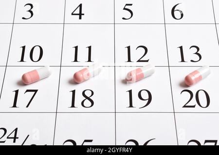 Medicinali. Capsule farmaceutiche rosa con compresse sono nel calendario. Un piano, un programma, un elenco o un calendario dei farmaci. Foto Stock