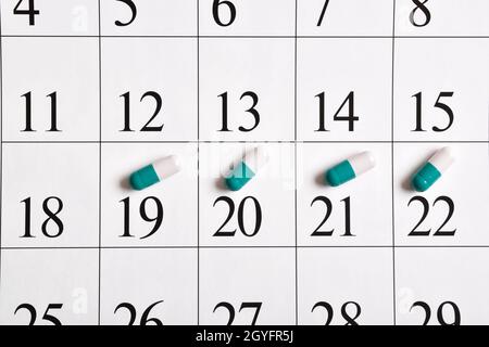 Medicinali. Un primo piano di capsule verdi con pillole è nel calendario. Un piano, un programma, un elenco o un calendario dei farmaci. Foto Stock