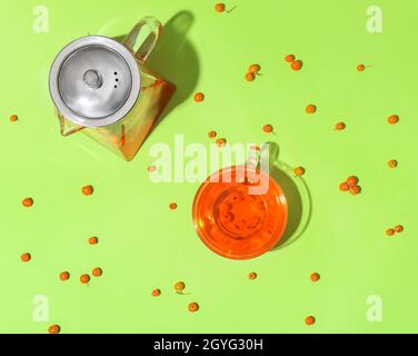 Tazza di vetro e teiera di gustoso tè rowan su sfondo verde Foto Stock