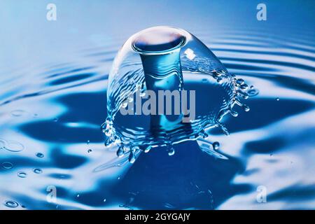 Collisione di due gocce d'acqua su acqua blu con increspature Foto Stock