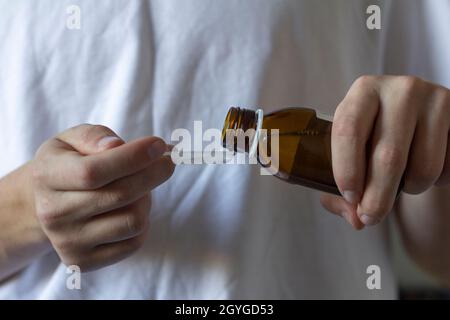 Un giovane versa la medicina in un cucchiaio da bere Foto Stock