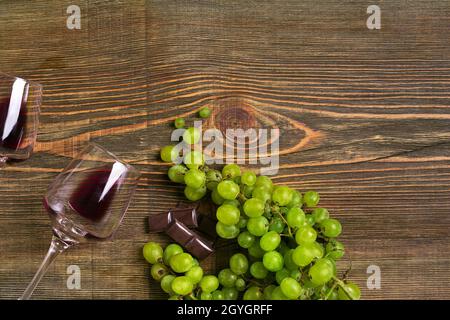 Bicchieri di vino e uva matura isolati su un tavolo di legno Foto Stock