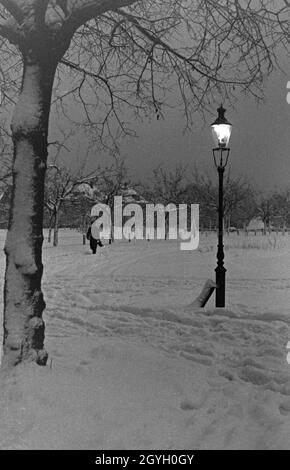 Eine persona geht in der Dämmerung im Schnee spazieren, Deutschland 1930er Jahre. Una persona passeggiando attraverso la neve all'alba, Germania 1930s. Foto Stock