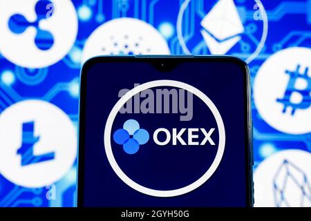 OKEx è uno scambio di criptovaluta. Logo OKEx sullo schermo dello smartphone sullo sfondo delle principali criptovalute. Foto Stock