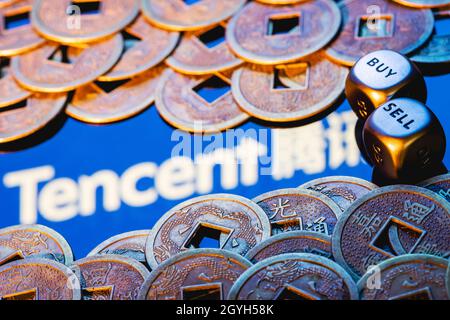 Morsi con le parole VENDERE COMPRARE. Il logo Tencent e le monete Feng Shui. Foto Stock