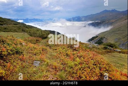 Paesaggio autunnale in montagna Alpi con macchia rossa e nuvole nella valle - col du petit saint Bernard Foto Stock