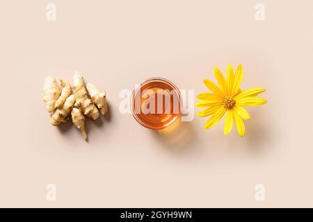 Topinambour o topinambour sciroppo in ciotola di vetro, fiore e radice su sfondo beige. Vista dall'alto. Stile minimalista. Disposizione piatta. Foto Stock