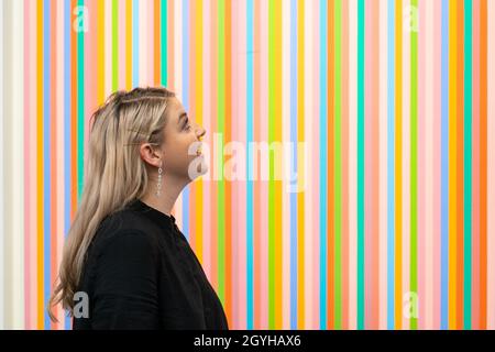 Un dipendente della casa d'aste di Sotheby vede 'Red Return' di Bridget Riley che si stima prelevi da 1 a 1.5 milioni di sterline come parte dell'asta d'arte contemporanea di Sotheby a Londra il 14 ottobre durante la settimana di London Frieze. Data foto: Giovedì 7 ottobre 2021. Foto Stock