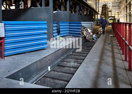Grodno, Belarus - Ottobre 2018: Il lavoratore offuscato in movimento controlla il processo di caricamento del cartone e della carta utilizzati selezionati dallo stoccaggio al trasportatore per la furt Foto Stock