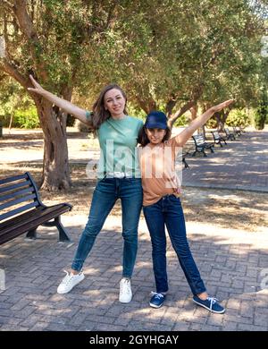 Madre di mezza età e sua figlia bambino in piedi nel parco all'aperto e guardando la macchina fotografica. Famiglia amorevole indossando t-shirt e jeans passare il tempo Tog Foto Stock