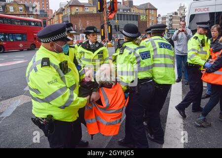 Londra, Regno Unito. 8 Ott 2021. La polizia rimuove e arresta i manifestanti della Gran Bretagna che si sono incollati alla strada alla rotonda di Old Street. I dimostranti insulati britannici chiedono che il governo isoli tutte le abitazioni sociali entro il 2025, e si assuma la responsabilità di garantire che tutte le case nel Regno Unito siano più efficienti dal punto di vista energetico entro il 2030, come parte di più ampi obiettivi di cambiamento climatico e decarbonizzazione. Credit: Vuk Valcic/Alamy Live News Foto Stock