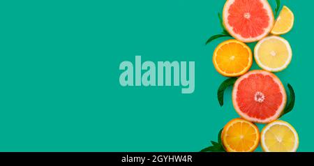 Sfondo di frutta colorato. Disposizione piatta. Idea creativa minimal food design con cornice di slice di agrumi sul layout menta. Arancio, limone, pompelmo e menta bor Foto Stock