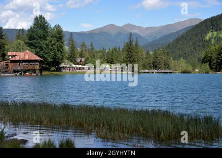 Un piccolo ponte in legno permette l'accesso alla riva destra, la zona più turistica del lago di Dobbiaco Foto Stock