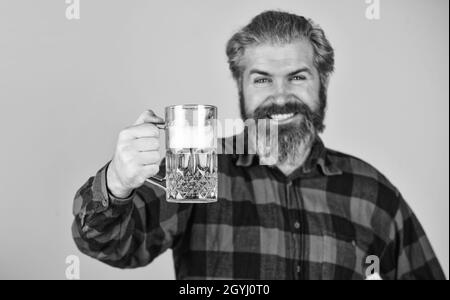 Brutale hippster bere birra. Relax e relax. Tempo di relax. Ideato per il divertimento di un party. L'artigiano del birrificio portava l'uomo tenere il bicchiere di birra. Tazza di alcol Foto Stock