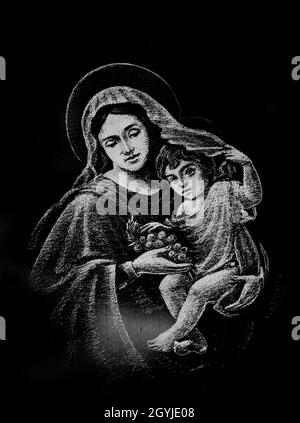 REGHIN, ROMANIA - 12 settembre 2021: Una foto verticale in scala di grigi di un'incisione in marmo raffigurante la Vergine Maria con il bambino Gesù nel cemetto ortodosso Foto Stock