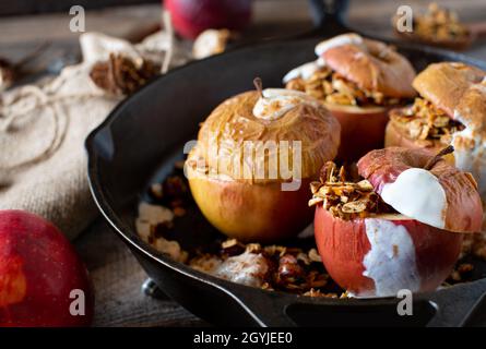 Cereali da colazione fatti in casa con mele appena sfornate e muesli con cannella e yogurt. Servito su un tavolo rustico e in legno. Foto Stock