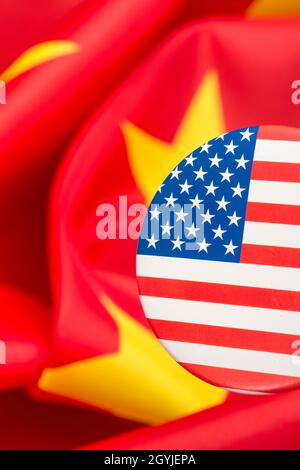 Il pulsante Stars and Stripes è contrassegnato dalla bandiera cinese gialla e rossa. Per la controversia USA-Cina, offshoring di lavoro USA alla Cina, metafora del Centro missione Cina degli Stati Uniti. Foto Stock