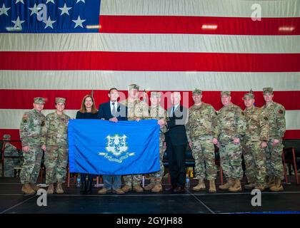 John Saunders e Major Cheryl Mead, leader per il 103esimo gruppo operativo e di manutenzione recentemente dispiegato, insieme al Gen. Francis Evon, il generale adjutant della Guardia Nazionale del Connecticut, il senatore degli Stati Uniti Richard Blumenthal, rappresentante degli Stati Uniti Joe Courtney, E la leadership della Guardia Nazionale aerea del Connecticut, presentano una bandiera di stato del Connecticut al Lt. Gov. Susan Bysiewicz durante una cerimonia di saluto alla base della Guardia Nazionale dell'aria di Bradley, East Granby, Conn. 4 gennaio 2020. La bandiera volò sopra la Siria durante una missione di combattimento su un aereo della Guardia Nazionale aerea del Connecticut C-130 Hercules. Foto Stock