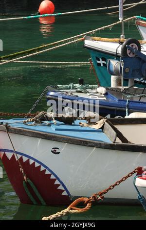 Gli archi di tre piccole imbarcazioni da pesca, una dipinta con denti Foto Stock