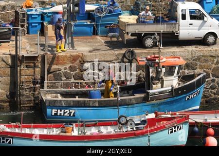 Fine della giornata di pesca per la piccola barca da pesca con la famiglia che aiuta a scaricare il pescato Foto Stock