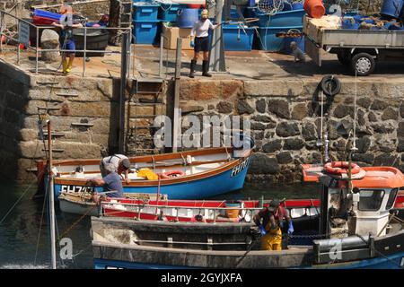 Fine della giornata di pesca per piccole barche da pesca con la famiglia a riva in attesa di aiutare a scaricare Foto Stock
