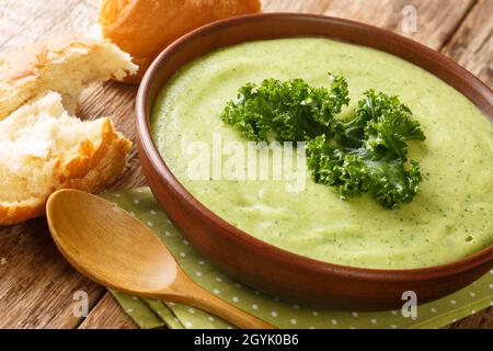 Zuppa di panna verde vegetariana a base di cavolo kale da vicino in una ciotola sul tavolo. Orizzontale Foto Stock