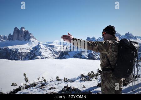 L'Esercito Italiano Luogotenente Ewald Beikircher, comandante della Ski and Climbing Platoon, 79th Company, VI Regiment Alpino, indica l'ex confine tra l'Austria e l'Italia, mentre guida i soldati della Riserva Esercito degli Stati Uniti dal 2500th Digital Liaison distaccment, 7° comando di supporto alla Missione, su una cima di Monte Specie durante la ricerca, Addestramento per il salvataggio e il recupero a Dobbiaco, Italia, 10-12 gennaio 2020. Quindici soldati del 2500 hanno partecipato alla formazione sulla sopravvivenza invernale che ha enfatizzato l'interoperabilità tattica delle piccole unità. Foto Stock