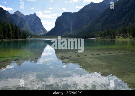 Cielo e montagne si riflettono nelle acque del lago di Dobbiaco in una giornata estiva Foto Stock