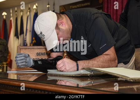 U.S. Army Master Sgt. (ret.) Leroy Petry firma il libro degli ospiti al GeneGeorge S. Patton Jr. Desk durante una visita alla settima Accademia non commissionata del comando di addestramento dell'Esercito a Grafenwoehr, Germania, 15 gennaio 2020. I veterani di combattimento sono associati alla Fondazione truppe prima (TFF), un'organizzazione che supporta i guerrieri feriti dopo il 9/11 facilitando visite in loco nelle aree di addestramento e nelle strutture mediche a beneficio terapeutico. (STATI UNITI Foto esercito di Markus Rauchenberger) Foto Stock