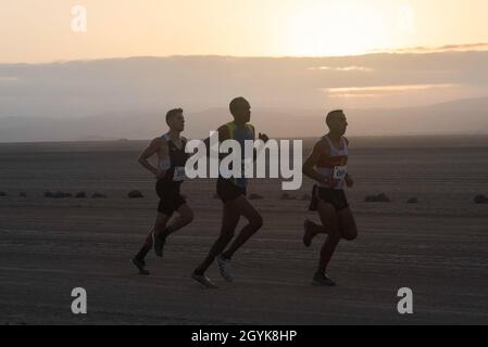 I partecipanti alla Grand Bara Race corrono lungo il sentiero 15k mentre il sole sorge sul deserto del Grand Bara, Gibuti, 15 gennaio 2020. I partecipanti seguirono una linea di rocce di 15 chilometri, originariamente posta dalla Legione straniera Francese. (STATI UNITI Air Force foto di Tech. SGT. Ashley Nicole Taylor) Foto Stock