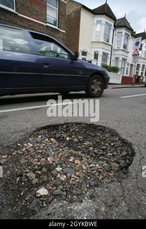 Foto di archivio datata 24/04/08 di un pothole in una strada a Tooting, SW London. Secondo una nuova analisi, i fondi annuali per più di 9.5 milioni di riparazioni di pothole sono stati persi dai bilanci del consiglio. La Local Government Association (LGA) ha dichiarato che il finanziamento complessivo del capitale del Department for Transport to Consilies in Inghilterra per la manutenzione stradale locale nel 2021/22 è di 1.39 miliardi di sterline, in calo rispetto ai 1.78 miliardi di sterline dell'anno precedente. Foto Stock