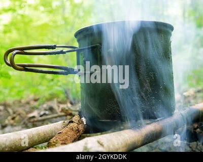 Cucina campo. Cucina sul fuoco durante l'escursione. Pentola appesa al fuoco Foto Stock