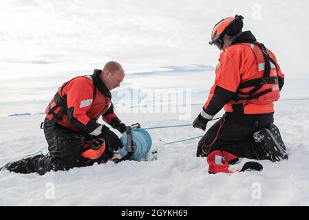 Guardia costiera degli Stati Uniti Petty Officer 1a Classe Kevin Lekich avvolge una bobina di linea di soccorso mentre Petty Officer 3a Classe Lance Kaufmann alimenta la linea il 19 gennaio 2020, circa 11 miglia a nord di McMurdo Station, Antartide. L'equipaggio della Guardia Costiera Cutter Polar Star (WAGB-10) partecipa all'operazione Deep Freeze, il contributo dei militari statunitensi al programma Antartico degli Stati Uniti, gestito dalla National Science Foundation. Fotografia della Guardia Costiera degli Stati Uniti da parte del Chief Petty Officer NyxoLyno Cangemi Foto Stock