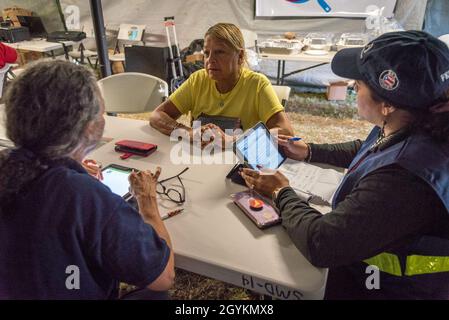 Guánica, PR, 21 gennaio 2020 -- i membri del team FEMA Disaster Assistance Margarite Ramirez e Marylina Colon registrano Estella Seranno, un dipendente della Guánica Munipatality Financial Services, per l'assistenza FEMA. I membri del team erano a disposizione presso il centro operazioni di emergenza per registrare tutti i soccorritori e i dipendenti governativi per ricevere assistenza a causa del recente terremoto. Foto di Liz Roll/FEMA Foto Stock