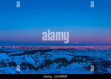 La Luna piena 'Cold' del 29 dicembre 2020 che sorge sopra le Badlands del Dinosaur Provincial Park, Alberta, sul fiume Red Deer, qui a sinistra. L'ultimo Foto Stock