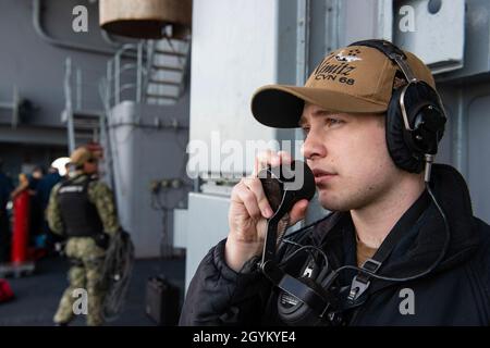 Operations Specialist 3rd Class Jacob Wagenaar, di Billings, da lunedì, parla in un telefono a potenza sonora sulla fantastica portaerei USS Nimitz (CVN 68) durante uno speciale dettaglio di mare e ancora. Nimitz sta attualmente conducendo operazioni di routine. (STATI UNITI Foto della Marina di Seaman Apprentice Kelsey Culbertson/rilasciato) Foto Stock