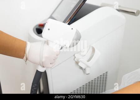 Lo specialista della rimozione dei capelli tiene in mano un laser Foto Stock