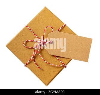 Scatola regalo di Natale con scheda di nota vuota, regalo di festa di carta kraft marrone con filo rosso bianco a righe legato arco tagliato isolato su sfondo bianco, Foto Stock