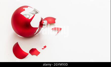 Natale bauble rotto isolato su sfondo bianco, vista closeup. La palla rossa di Natale si è schiantata a pezzi. Incidente di vacanza, fragilità, rabbia concetto Foto Stock