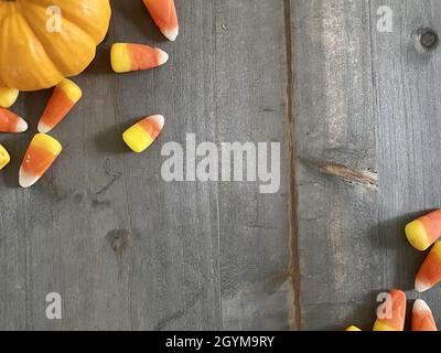 Vista dall'alto di una zucca e di un cornicione di caramelle su un tavolo grigio in legno con spazio copia Foto Stock