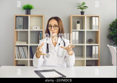 Ritratto di videochiamata di un medico professionista seduto alla scrivania dell'ufficio e che parla Foto Stock